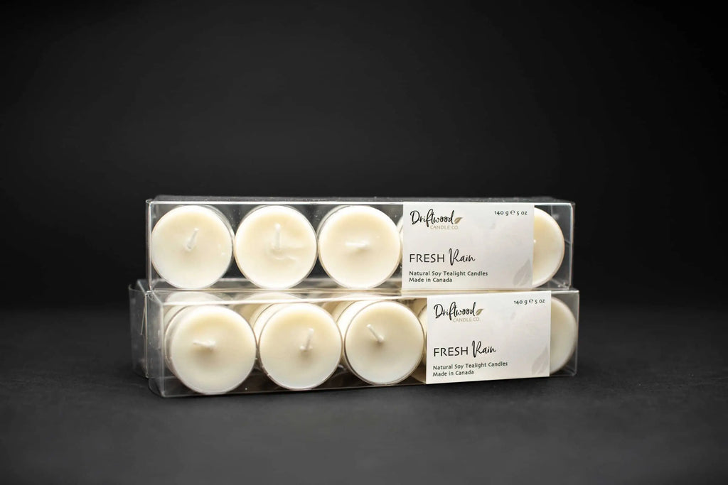 Two clear tealight boxes filled with ten soy tealights each.  Each box is labelled with Driftwood Candle co. label for Fresh Rain scent.