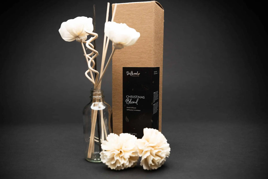Display of Christmas Blend Reed Diffuser set on black background.  Image includes packaging, samples of sola flowers and reed diffusers included in box.