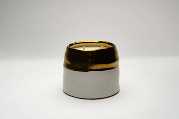 Dual toned ceramic jar filled with two wicks and soy wax.  Bottom of jar is white ceramic top is a thick gold band.